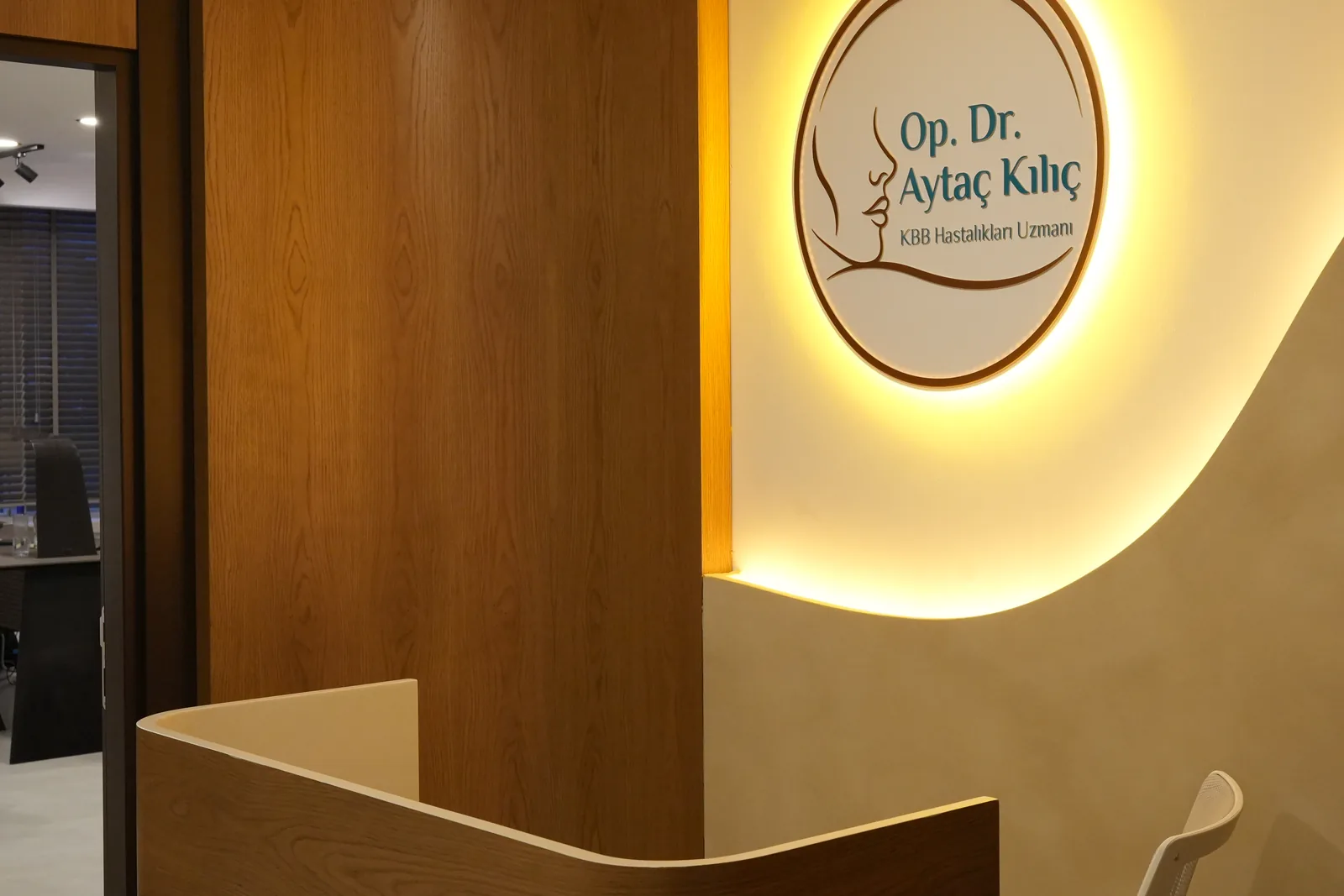 Reception desk of the practice with the illuminated Op. Dr. Aytac Kilic logo behind it