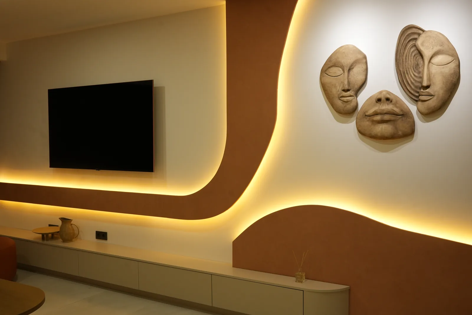Three stone face sculptures and a curved, backlit wall detail in the waiting lounge